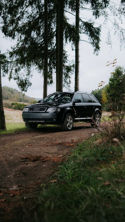 Dunkler Audi allroad auf einem Weg am Waldrand
